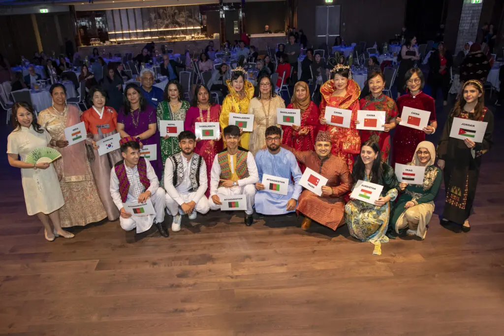 Culturally diverse group celebrates Settlement Refugee Week 2024 in traditional attire.