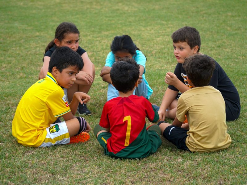 Child Safety Soccer Tournament Children sit in a circle on a soccer field during a Child Safety Soccer Tournament.